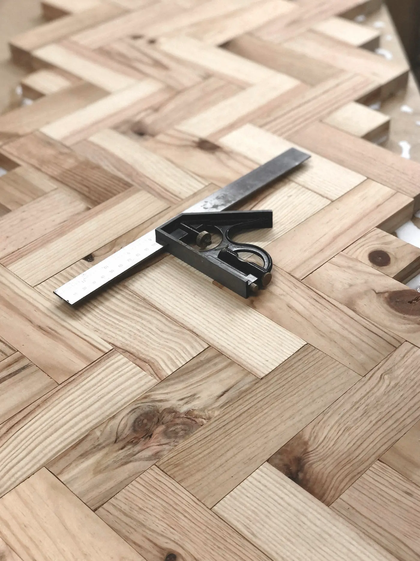 Équerre de menuisier posée sur un parquet en bâton rompu