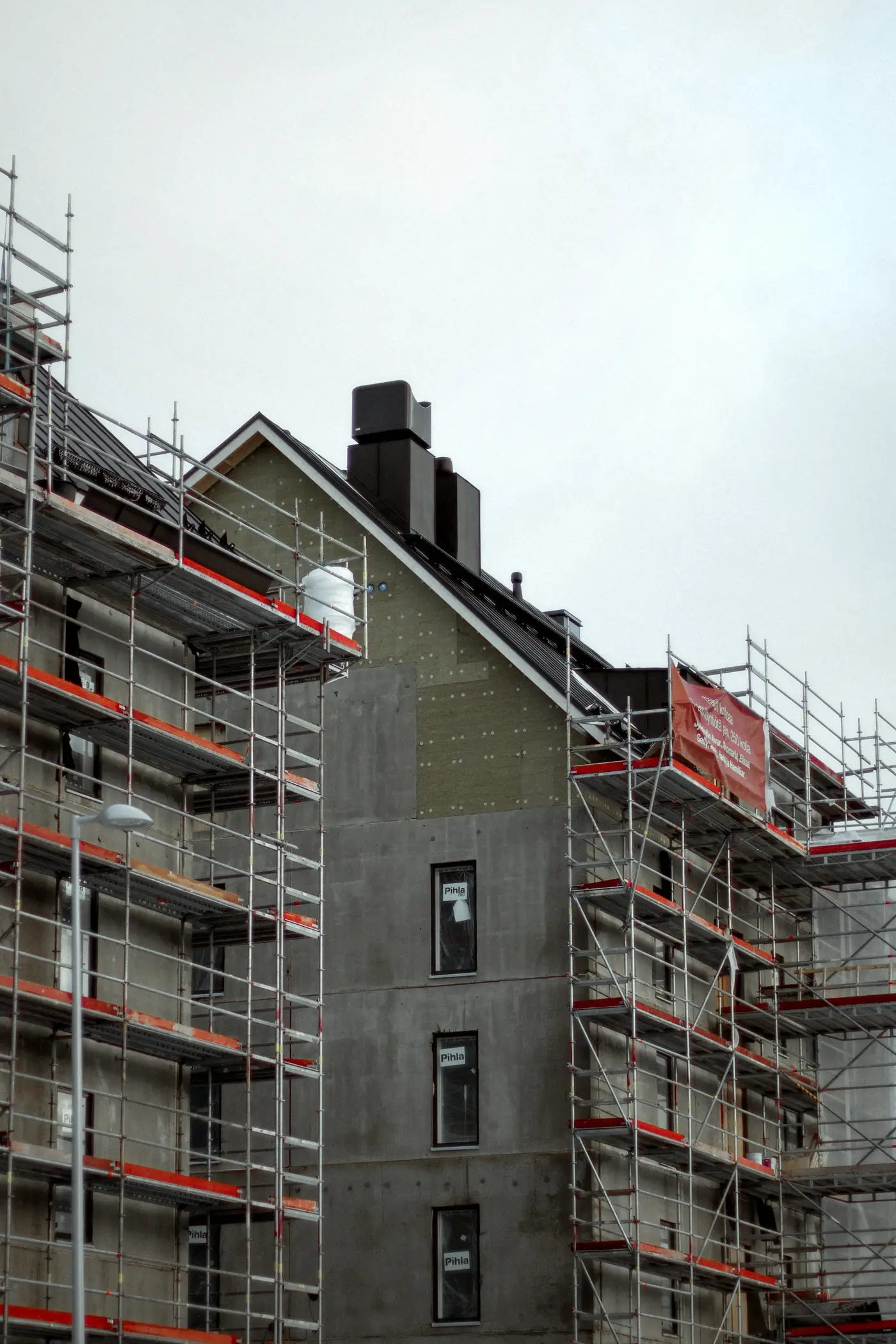 Maison sous échafaudage dont la façade reçoit des panneaux isolants