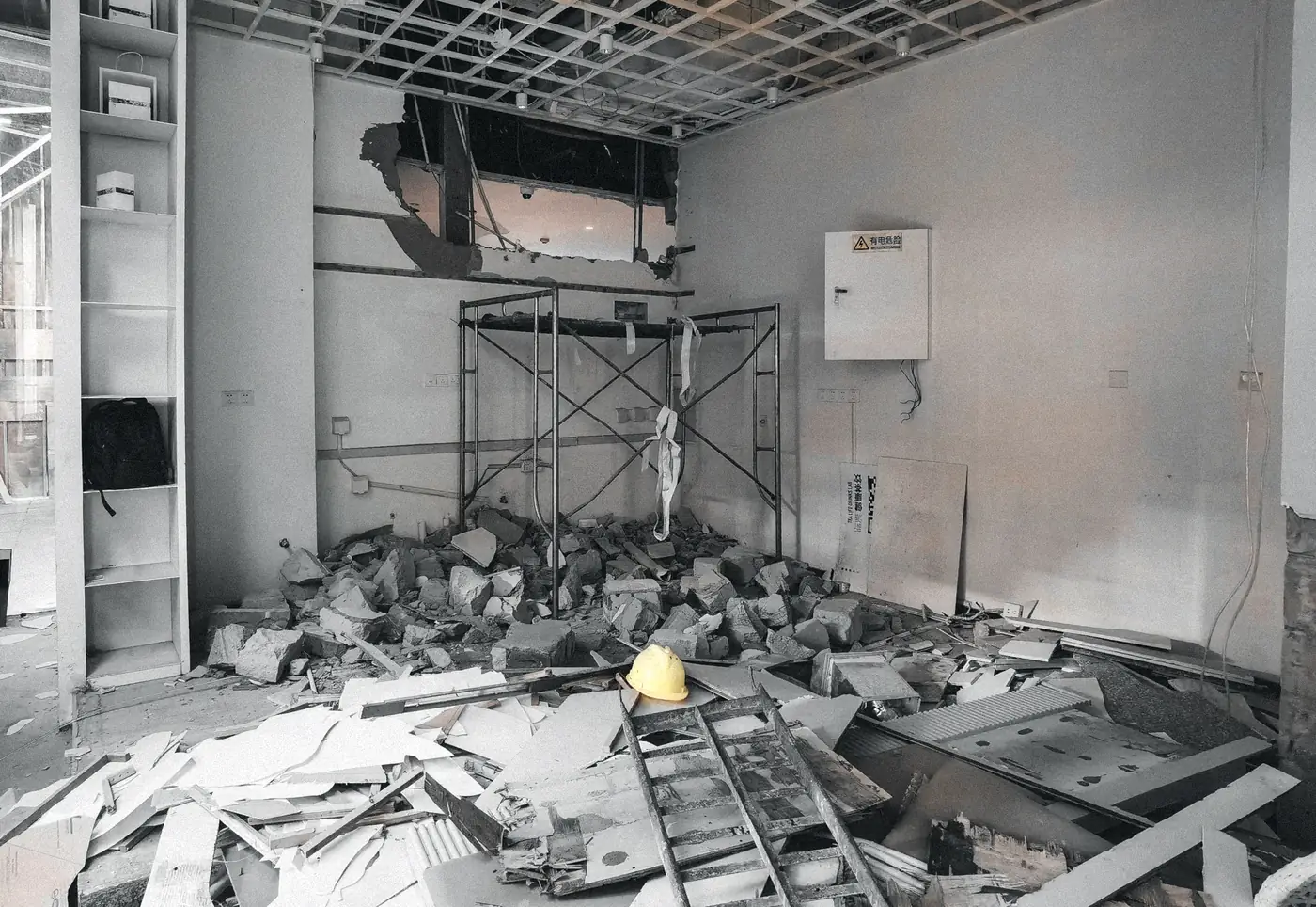 Pièce démolie : gravats au sol, plafond ouvert et échafaudage roulant