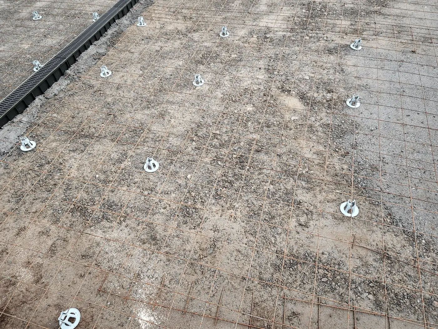 Treillis soudé posé sur cales au-dessus d’un hérisson, avant le coulage d’une allée en béton